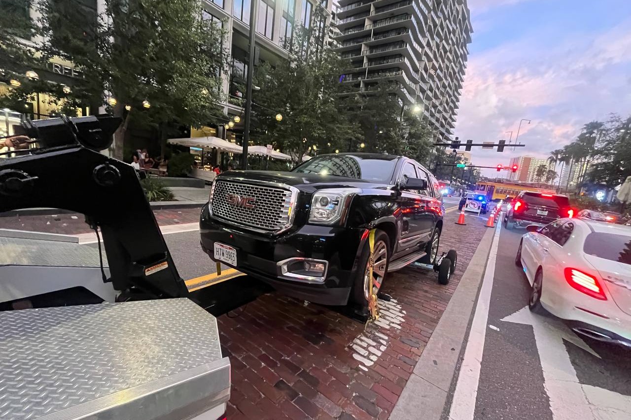 Tow truck loading a car in a Tampa apartment complex parking lot at night — private property towing