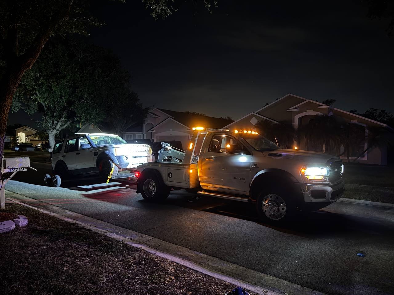 Ybor City Towing flatbed truck loading Land Rover at night in Tampa residential area